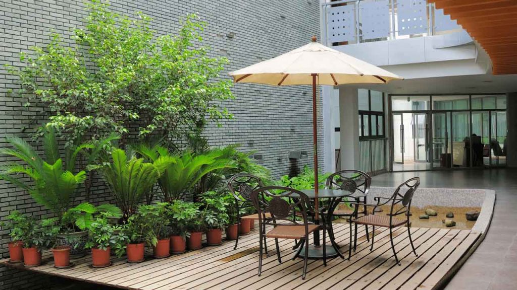 Outdoor courtyard patio with dining table, umbrella and potted plants