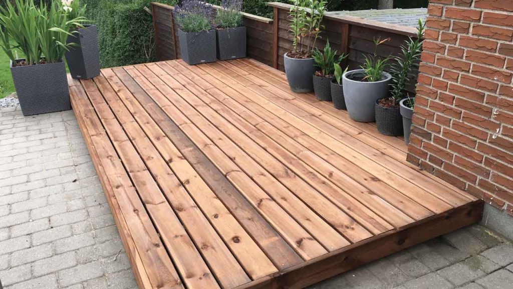 Outdoor deck with lounge seating overlooking water and hills at sunset