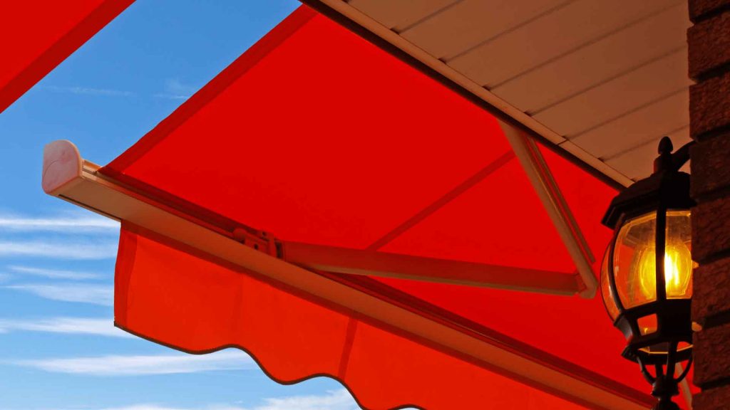 Close-up of a red retractable awning fitted beneath a roofline