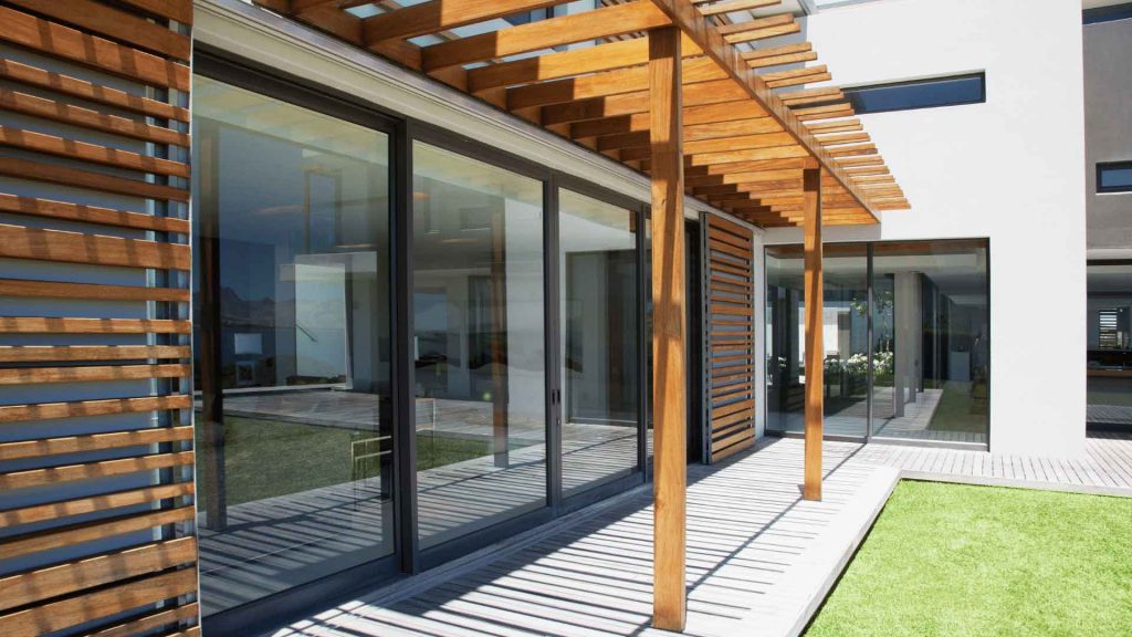 Modern home exterior with a timber pergola walkway and glass sliding doors