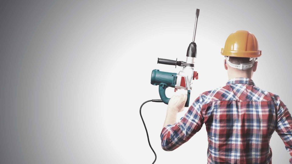 Tradesperson in a hard hat holding a rotary hammer drill