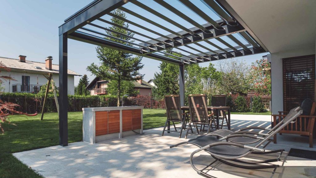 Outdoor pergola structure over a paved patio with outdoor kitchen and seating