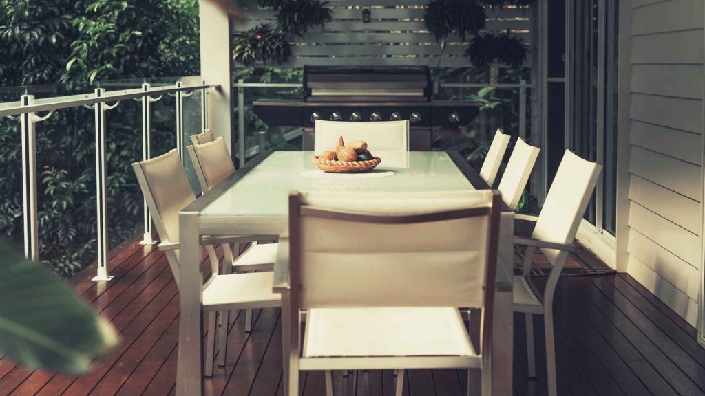 Timber deck and verandah with glass balustrade and outdoor BBQ setting
